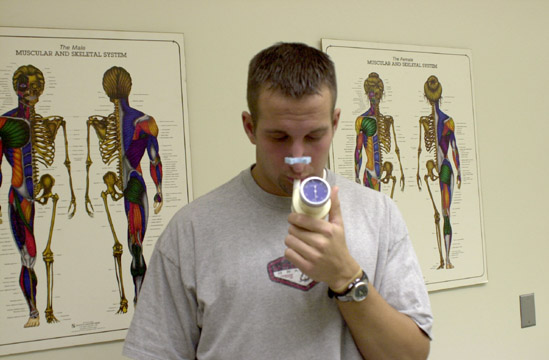 A student breathing into a device to test vital capacity